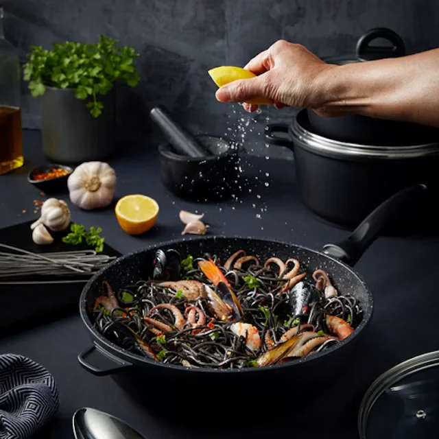 Global Retail Brands cookware: a frying pan of seafood pasta with lemon being squeezed over it